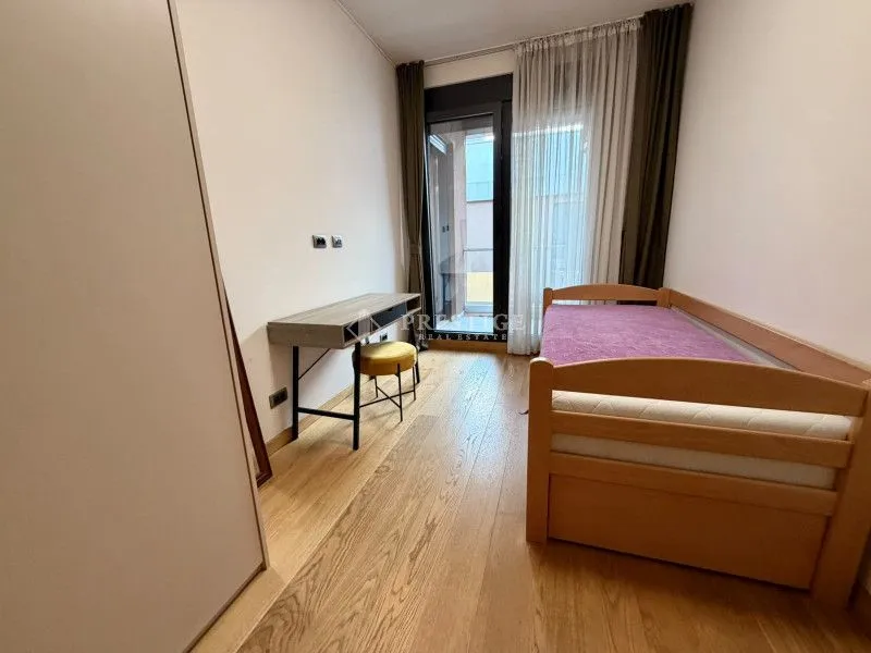 Namještena spavaća soba sa krevetom, radnim stolom i izlazom na terasu.