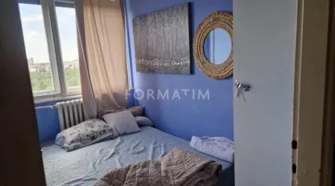 Manja spavaća soba sa krevetom, prozorom i ukrasnim ogledalom na plavom zidu. - image 3