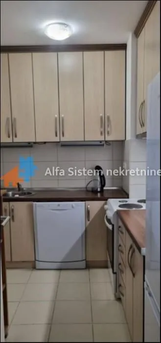 Manja kuhinja sa drvenim elementima, belom tehnikom i keramičkim pločicama.