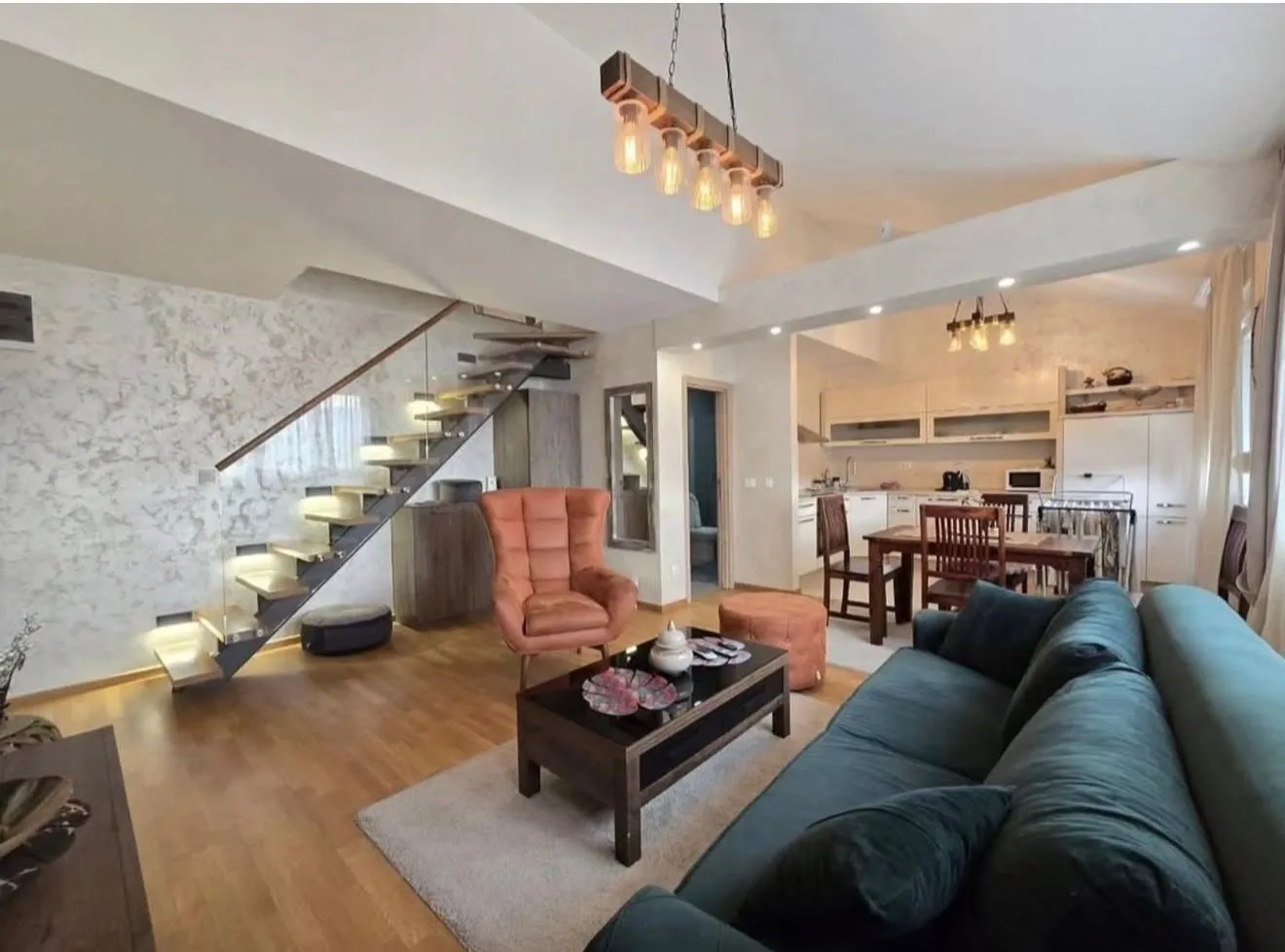 Modern open-space living room with dining area, kitchen and internal staircase.