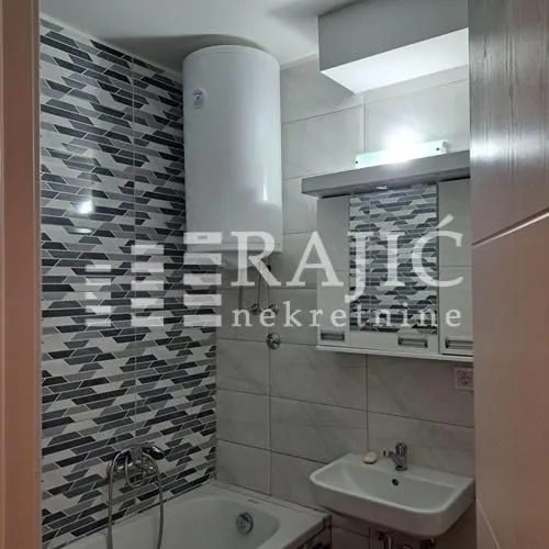 View of a furnished bathroom with a bathtub, washbasin, and water heater.