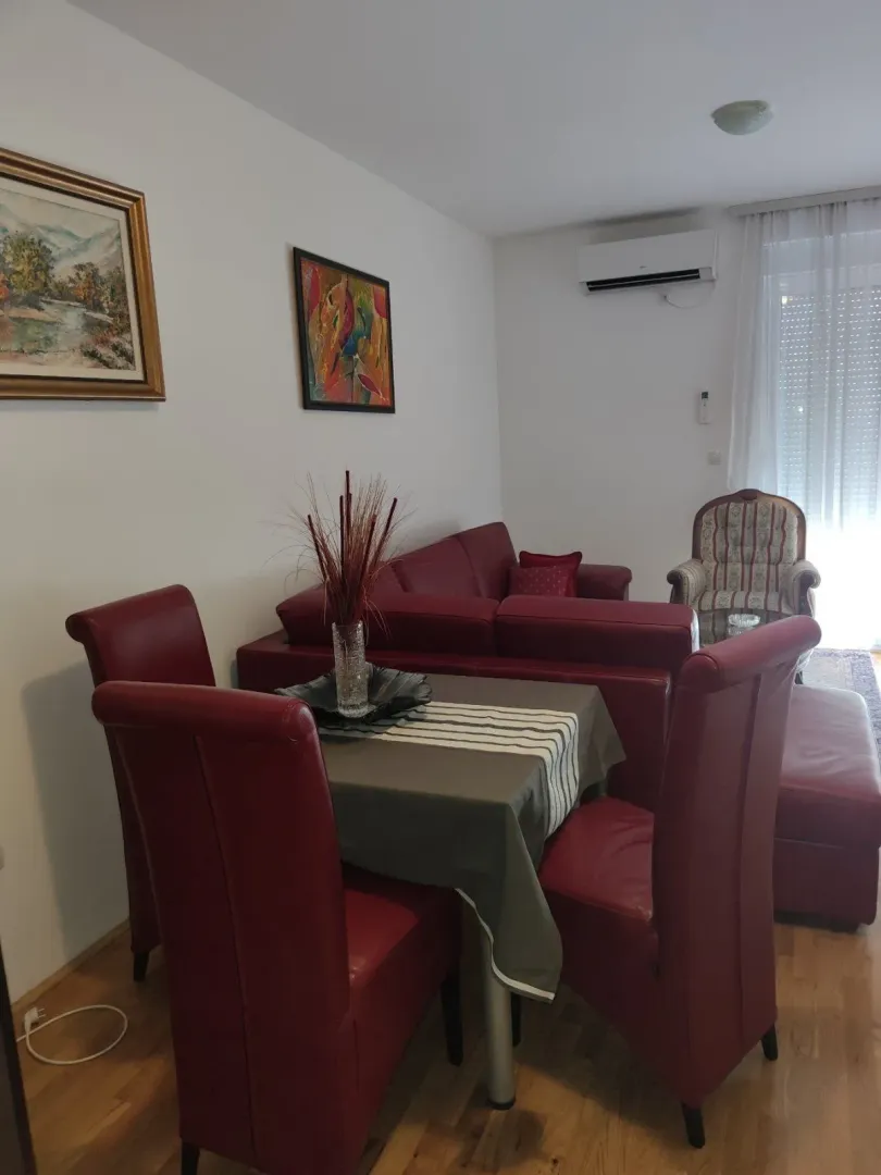 Bright living room featuring a red corner sofa and a dining table.