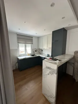 Moderna kuhinja sa mermernom radnom površinom i tamnim elementima. - image 3