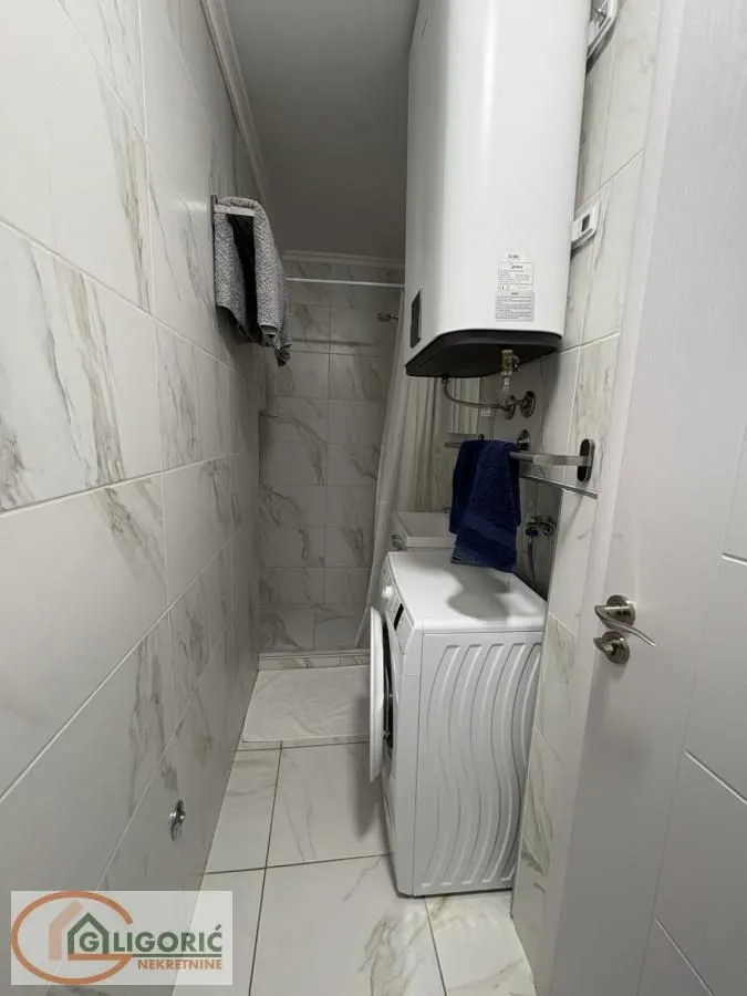 Small bathroom with a shower cabin, water heater, and washing machine.