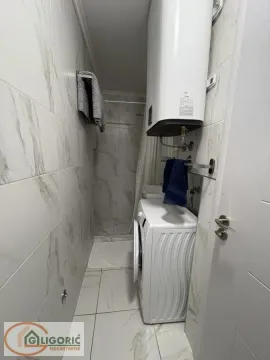 Small bathroom with a shower cabin, water heater, and washing machine. - image 10