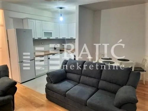Living room with a sofa and a view of the kitchen and dining area.
