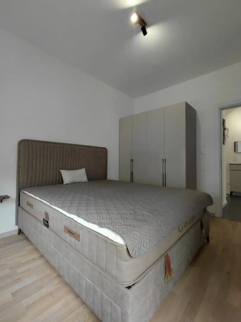 Svjetla spavaća soba sa bračnim krevetom i ormarom.