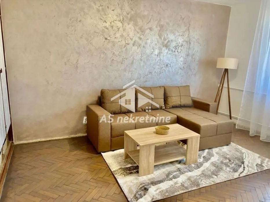 Living room with a sectional sofa, coffee table, and parquet flooring.