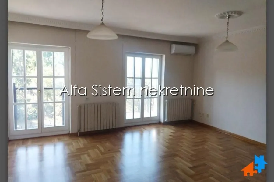 Empty living room with parquet flooring and double doors.