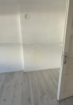 Prazna prostorija sa belim zidovima i svetlim laminatom. - image 6