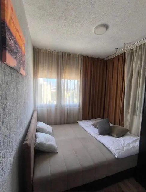 Bedroom with a double bed and a window with curtains.