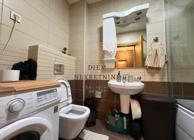 Compact bathroom with a sink, toilet, washing machine, and shower cabin.