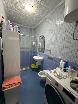 Manje kupatilo sa plavim pločicama, tuš kabinom i veš mašinom. - image 5
