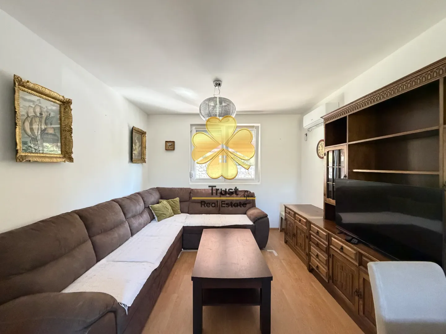 Living room with a sectional sofa, wooden furniture, and paintings on the wall.