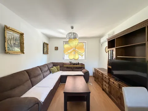 Living room with a sectional sofa, wooden furniture, and paintings on the wall. - image 2
