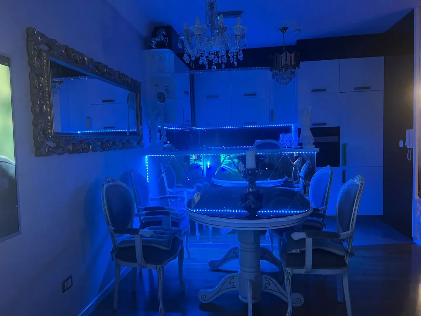 Trpezarija sa stolom, stolicama i plavim led osvjetljenjem.