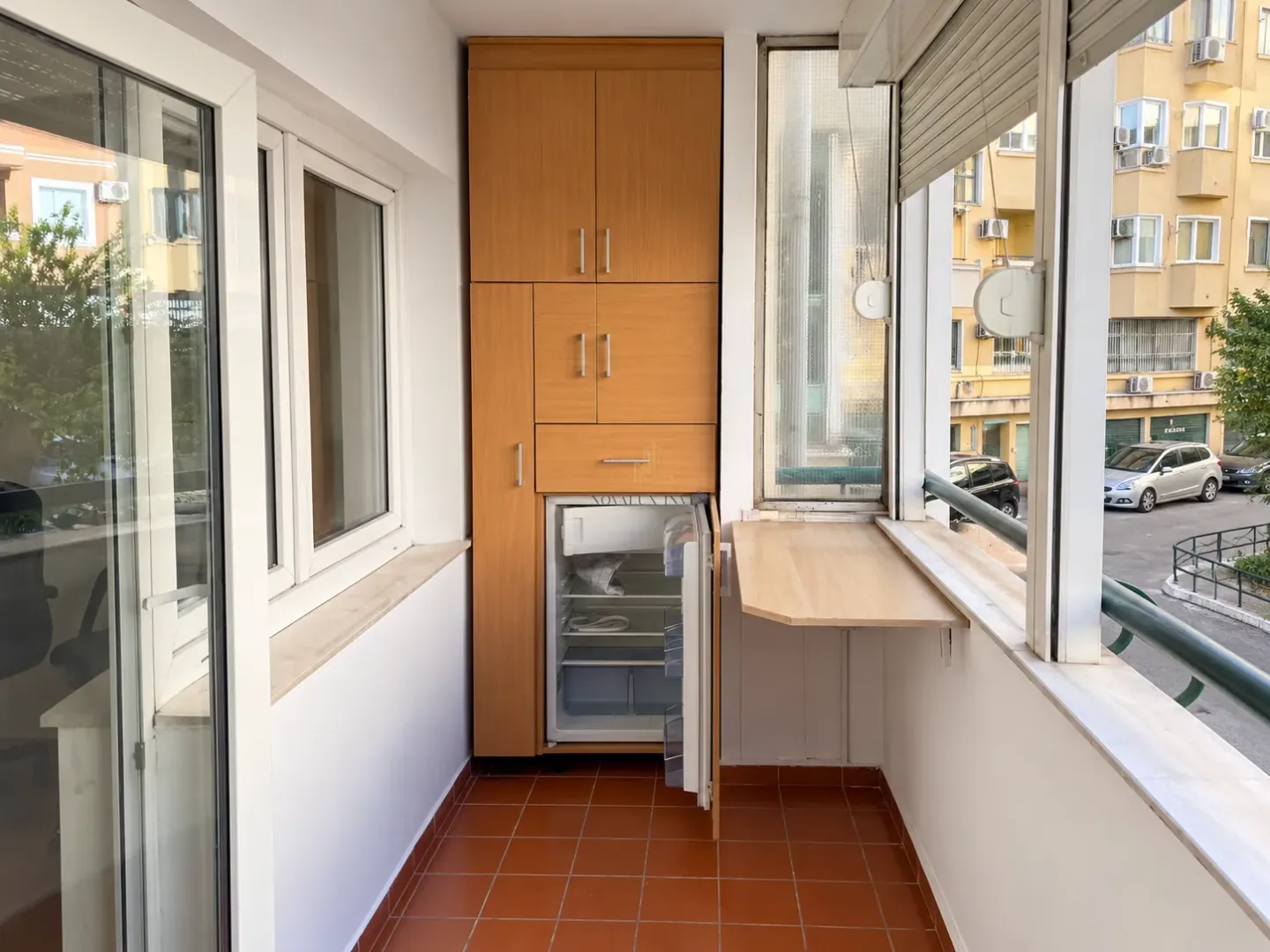 Enclosed balcony with built-in cabinetry and a small refrigerator.