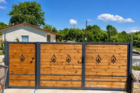 Wooden courtyard gate with a metal frame and a house in the background. - image 15