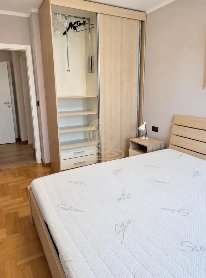 Spavaća soba sa bračnim krevetom, noćnim stočićem i ugradnim ormarom.