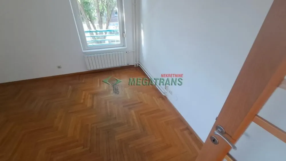 Prazna soba sa parketom i prozorom.