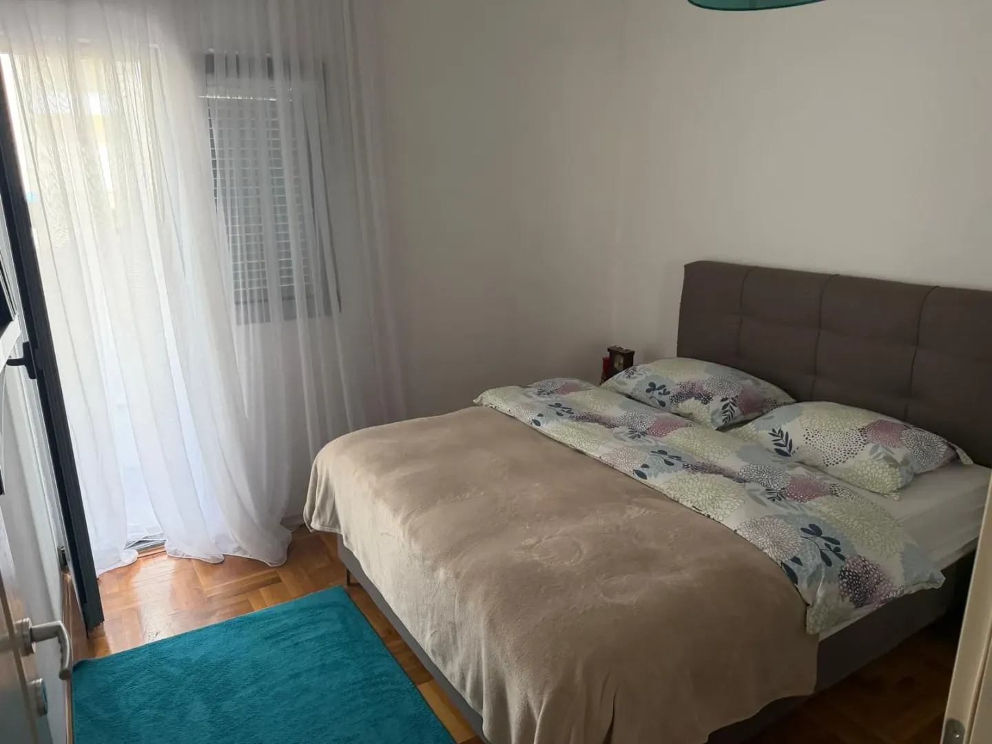 Namještena spavaća soba sa bračnim krevetom i izlazom na terasu.