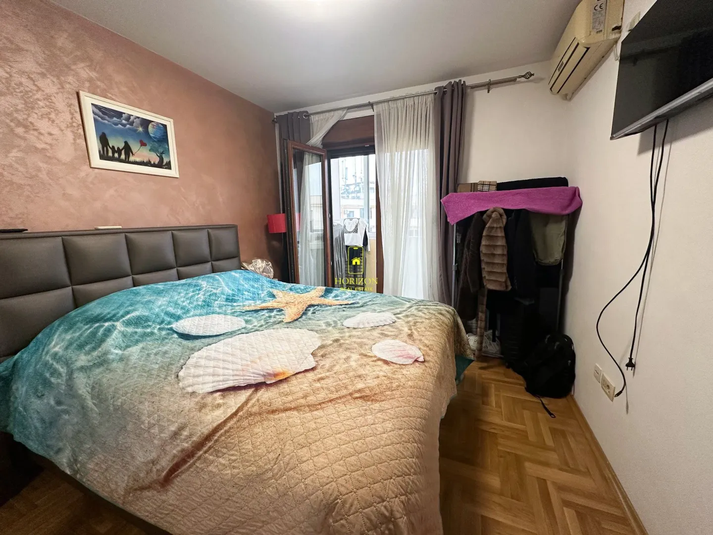 Namještena spavaća soba sa bračnim krevetom i izlazom na terasu.