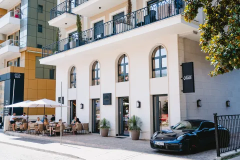 Exterior of a modern multi-story building with ground-floor commercial space and a cafe terrace. - image 6