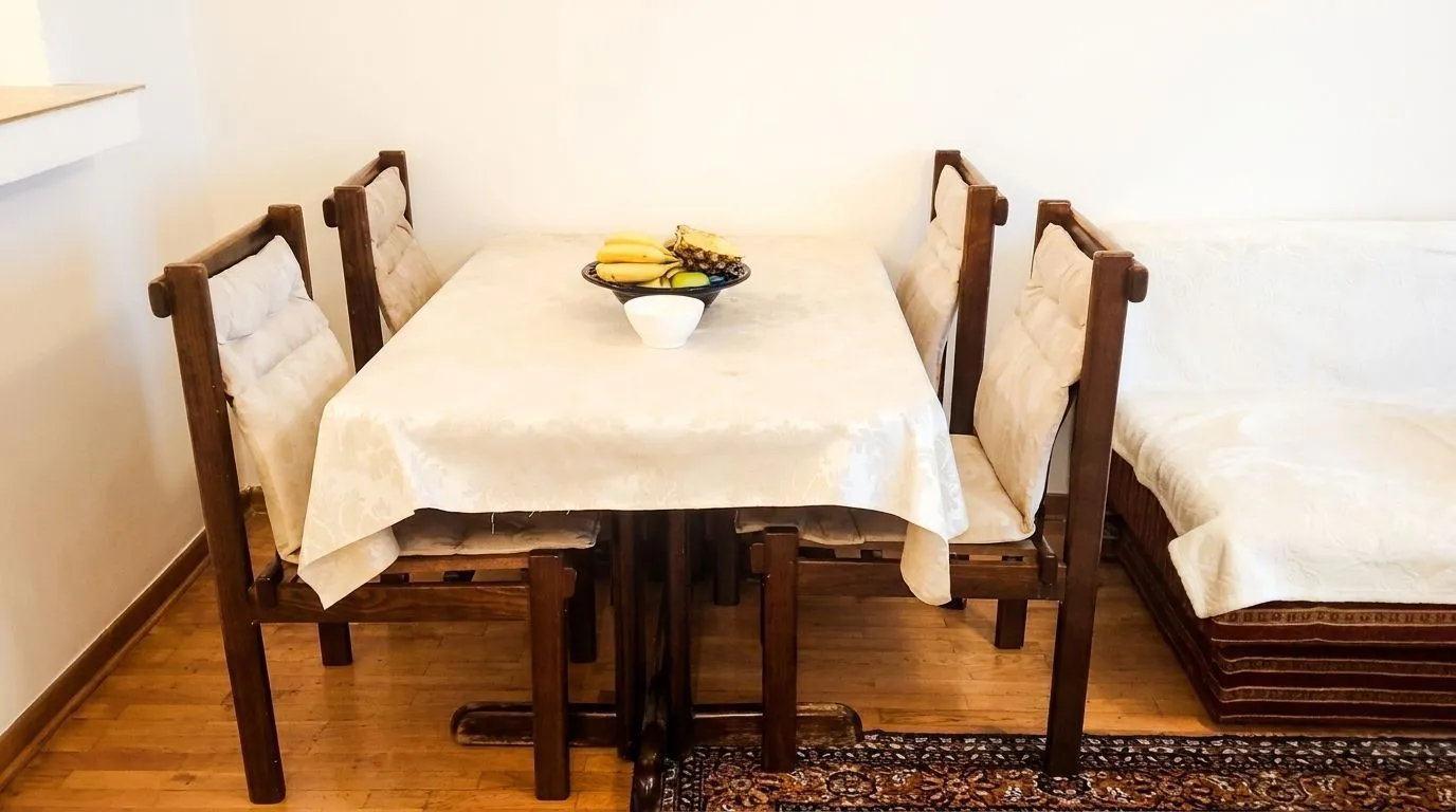 Dining table with wooden chairs and a bowl of fruit in the living room.