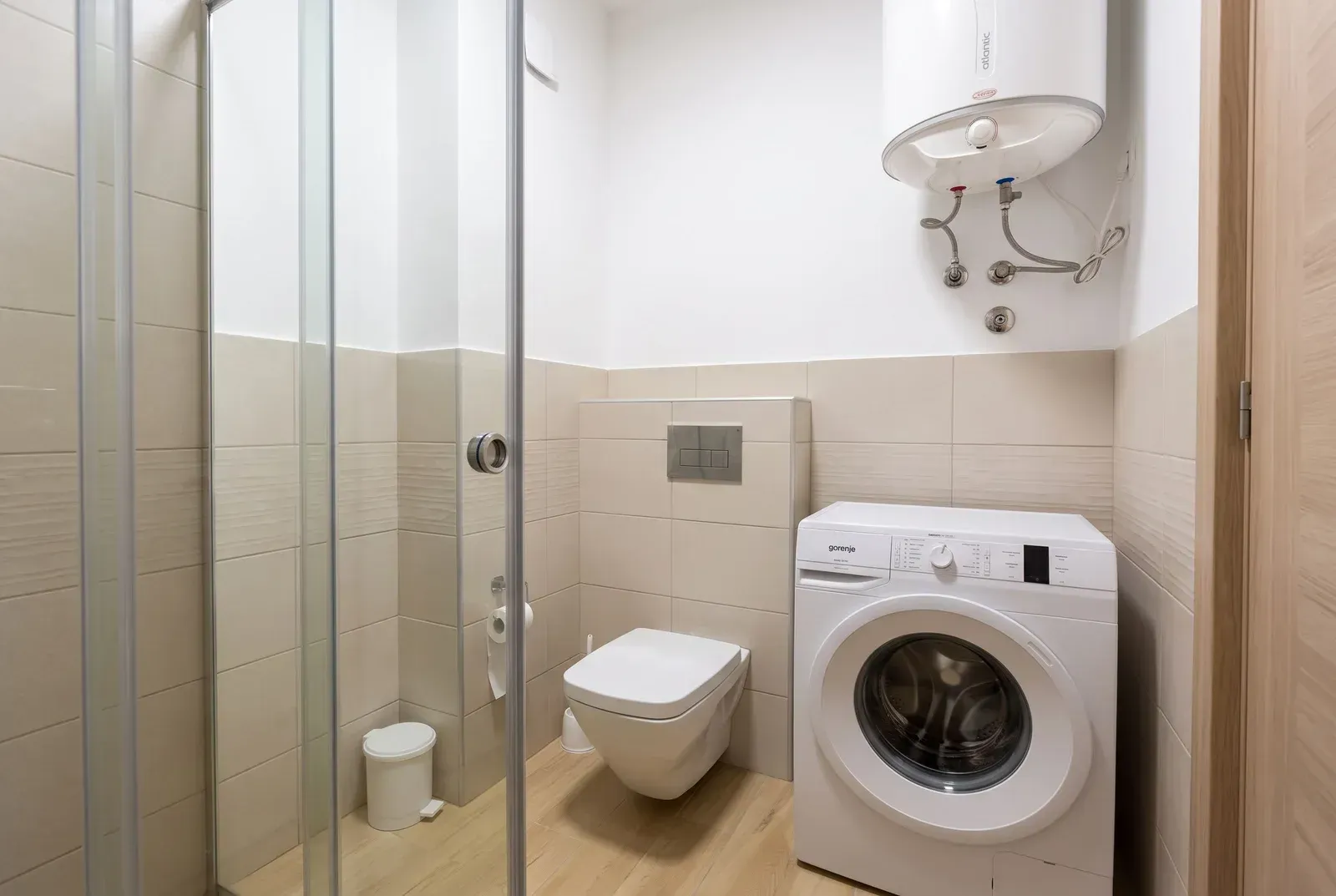 Moderne kupatilo sa tuš kabinom, WC šoljom i veš mašinom.