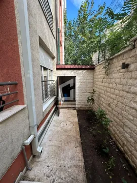 Manje dvorište pored zgrade sa popločanim stazama i malom baštom. - image 2