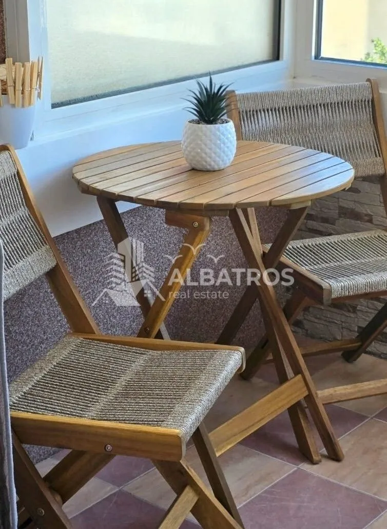 Small wooden table with chairs on a glazed balcony.