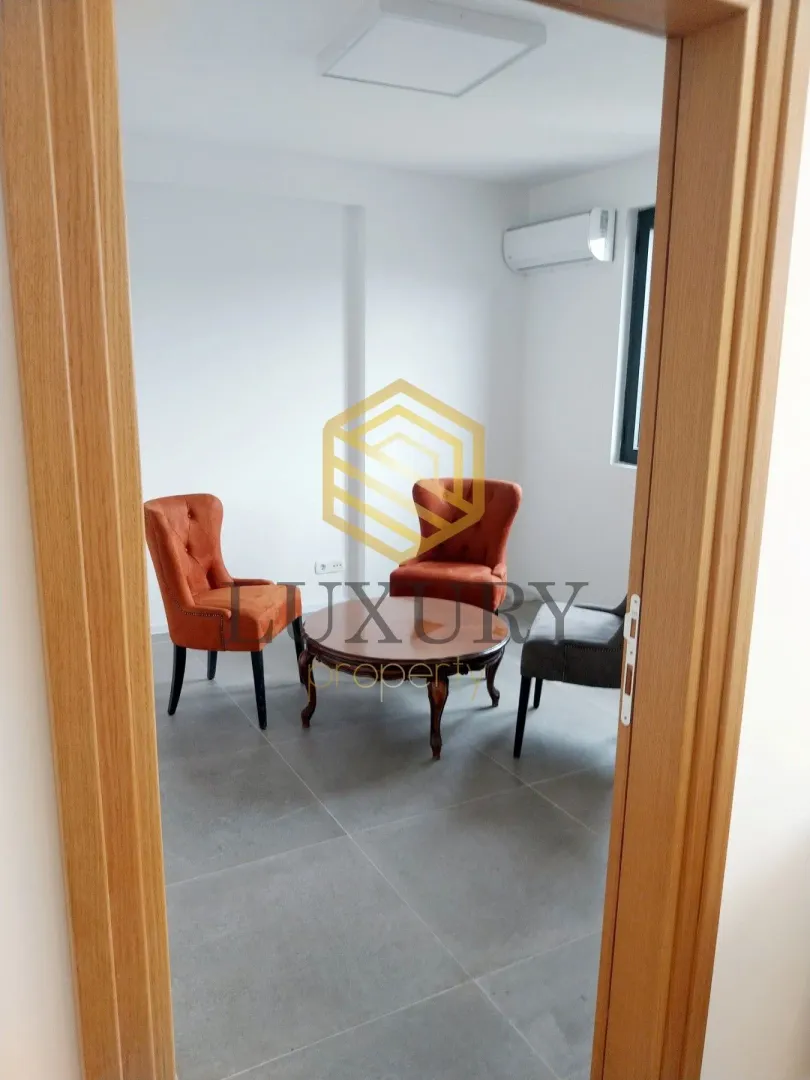 Living room with armchairs and a coffee table, viewed through a doorway.