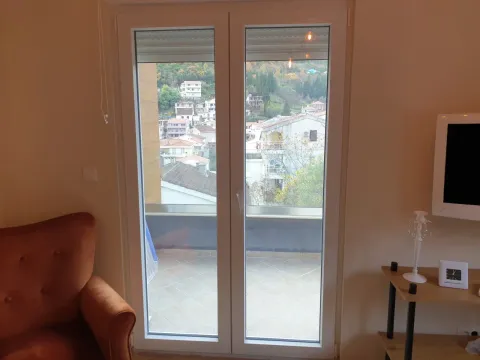 Dnevna soba sa balkonskim vratima i pogledom na naselje. - image 4