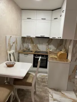 Small white kitchen with a dining table and built-in appliances. - image 2