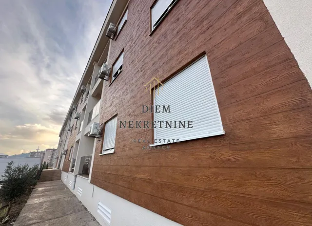 Exterior view of a residential building with a wooden facade and roller blinds.