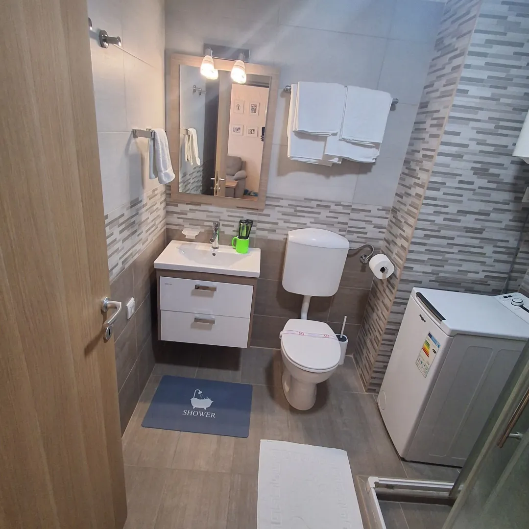 Moderne kupatilo sa umivaonikom, WC šoljom, tuš kabinom i veš mašinom.