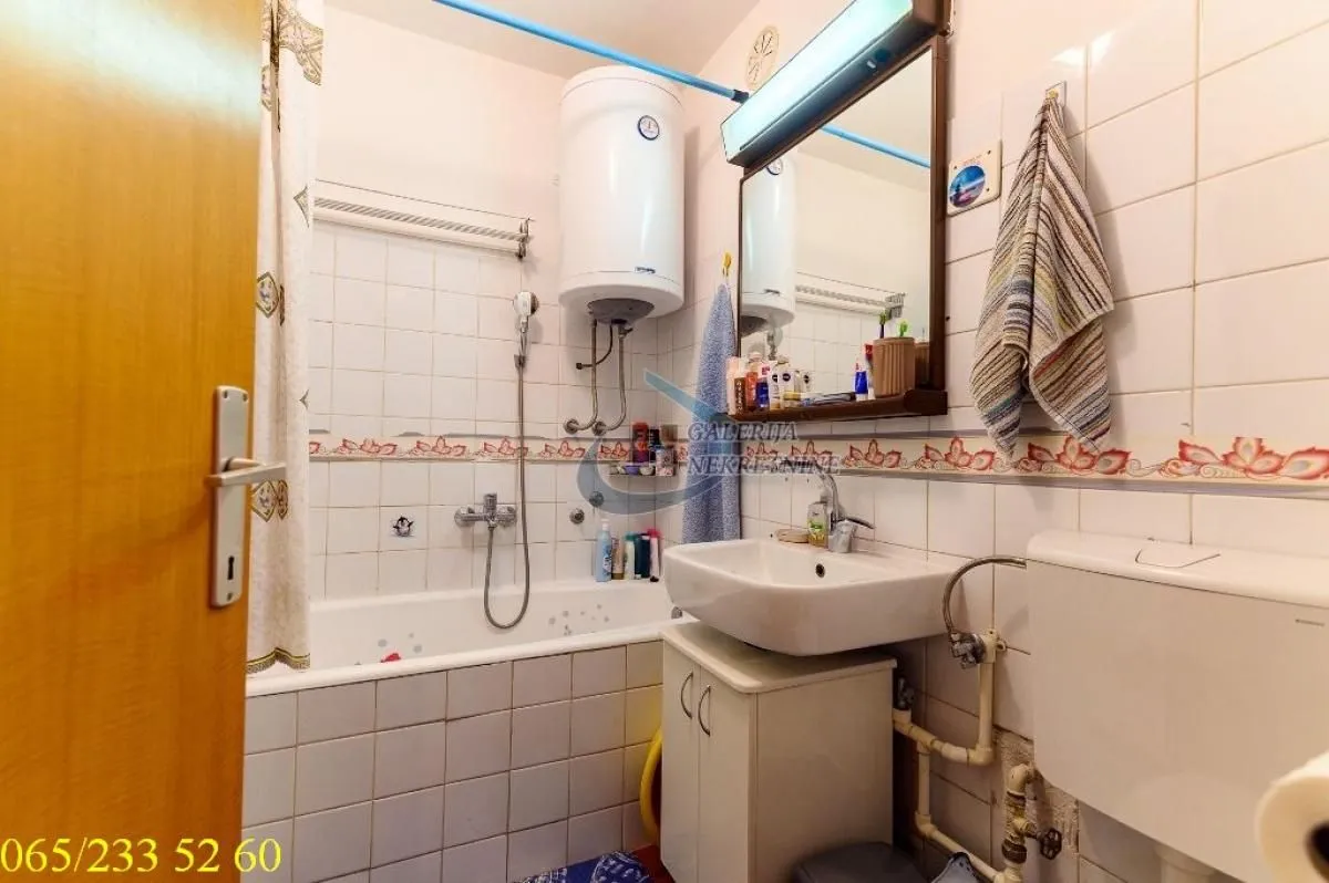 Smaller bathroom with a bathtub, washbasin, water heater, and toilet.