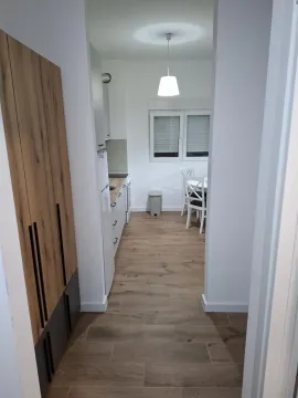 View from the hallway into a bright kitchen with a dining area. - image 7