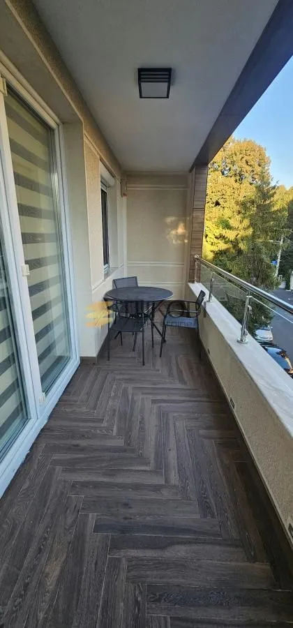 Natkrivena terasa sa garniturom za sedenje i podom u imitaciji drveta.