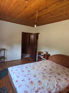 Spavaća soba sa bračnim krevetom, drvenim plafonom i vratima koja vode u hodnik. - image 13
