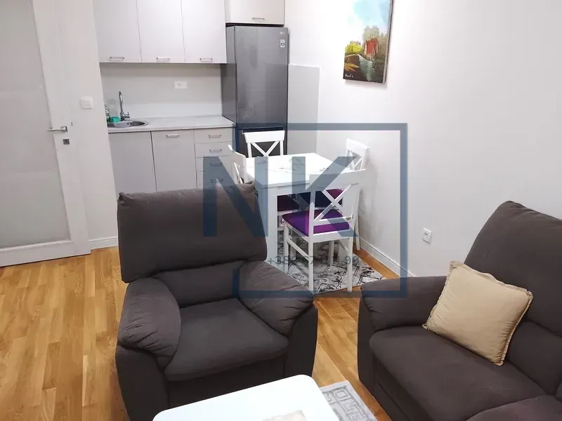 Living room with a sofa set, dining area, and fitted kitchen in the background.
