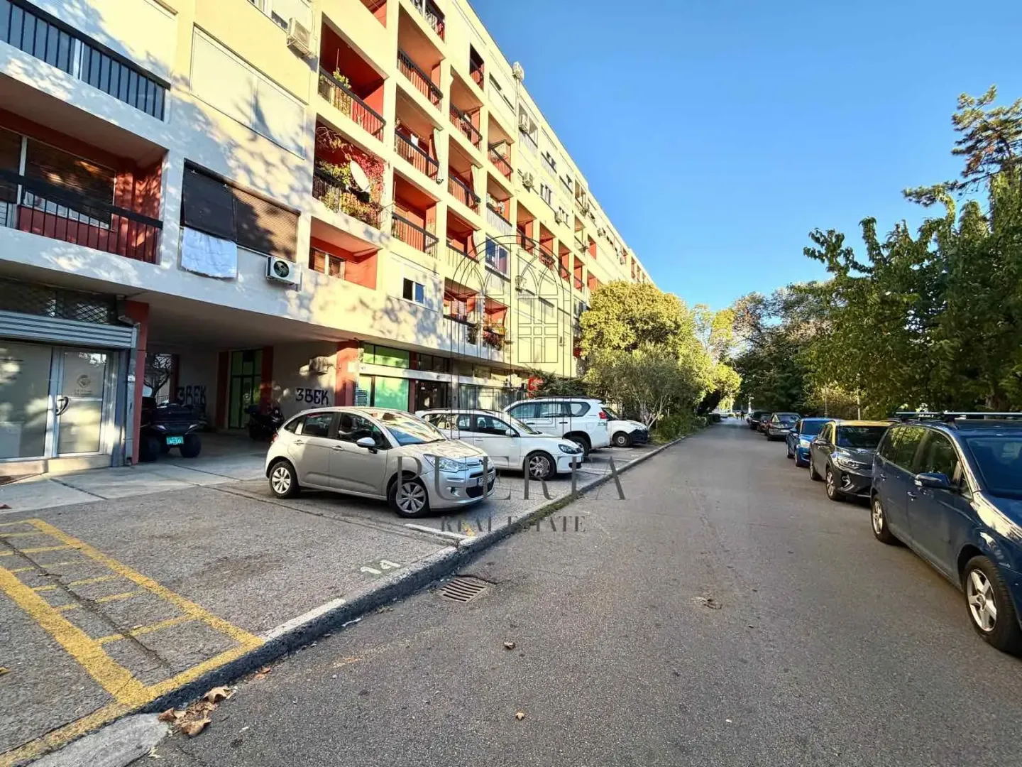 Exterior view of an apartment building and parking lot with parked cars.