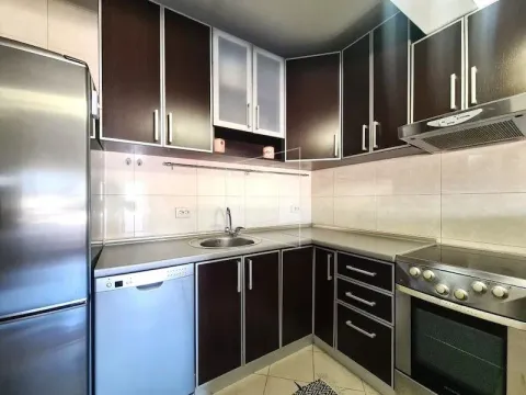 Small kitchen with dark cabinets, a sink, and built-in appliances. - image 4