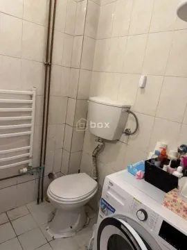 Manje kupatilo sa toaletom i veš mašinom obloženo svetlim pločicama. - image 5