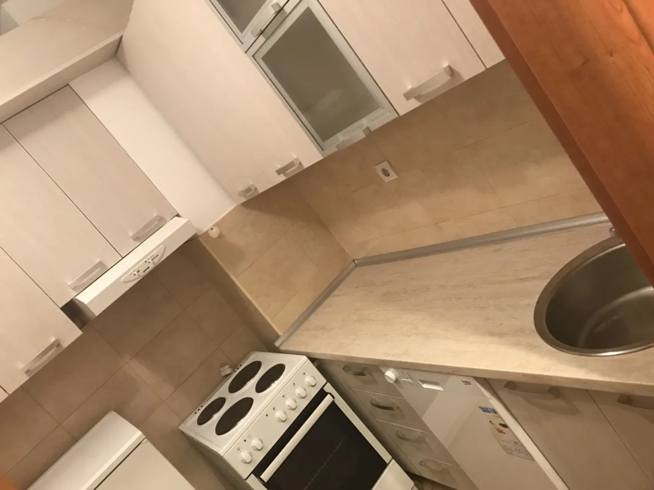 Kuhinja sa bijelim elementima, šporetom i radnom površinom.
