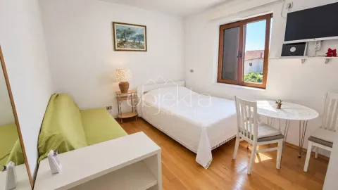 Furnished bedroom with a bed, green sofa, dining table, and a window. - image 2