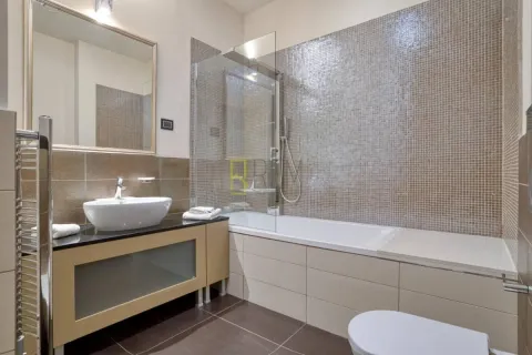 Modern bathroom with a bathtub, glass shower screen, and washbasin. - image 9