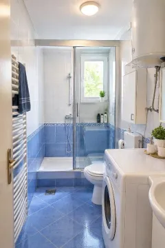 Compact bathroom with a shower cabin, toilet, and washing machine. - image 13
