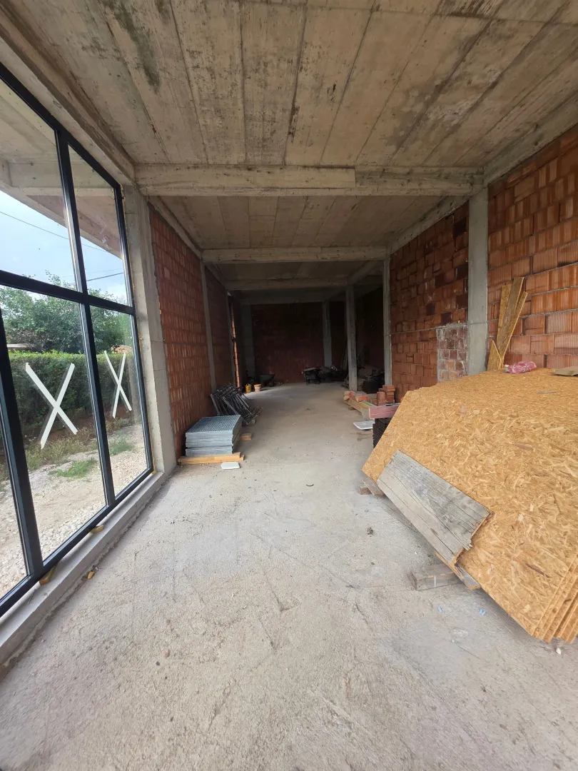 Unfinished space under construction with concrete columns and windows.