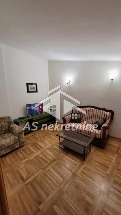Dnevna soba sa garniturom za sedenje, stočićem i televizorom.